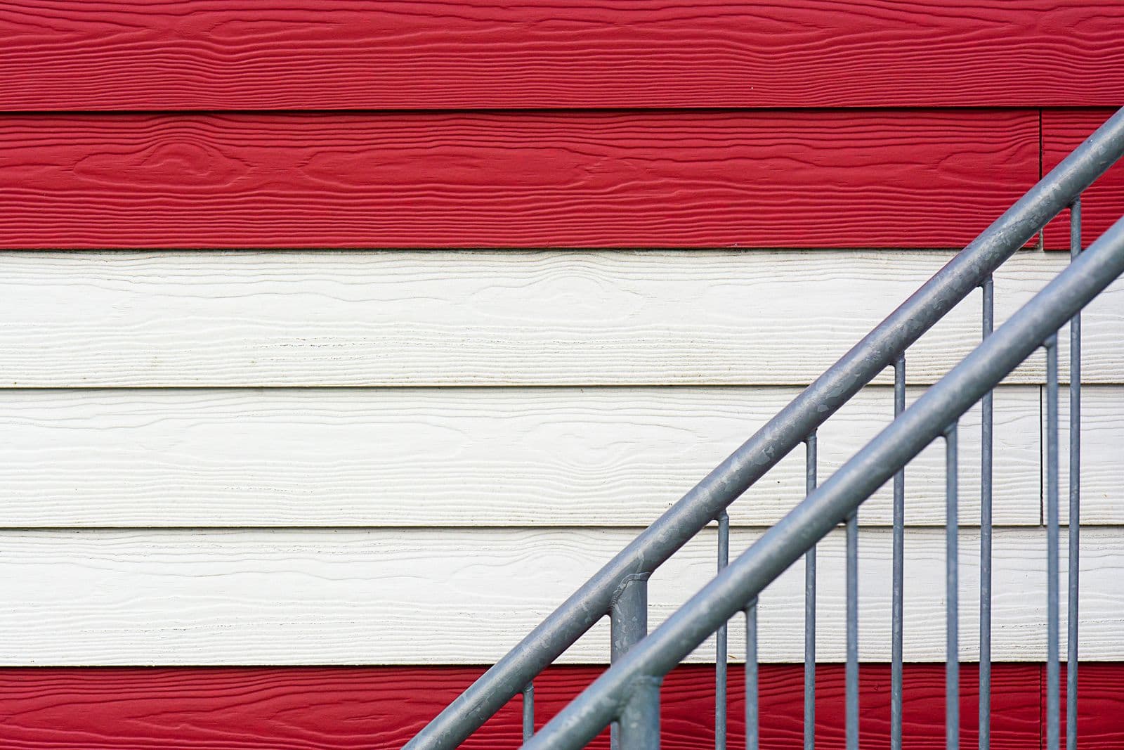 Red and white lap siding behind a metal stair rail
