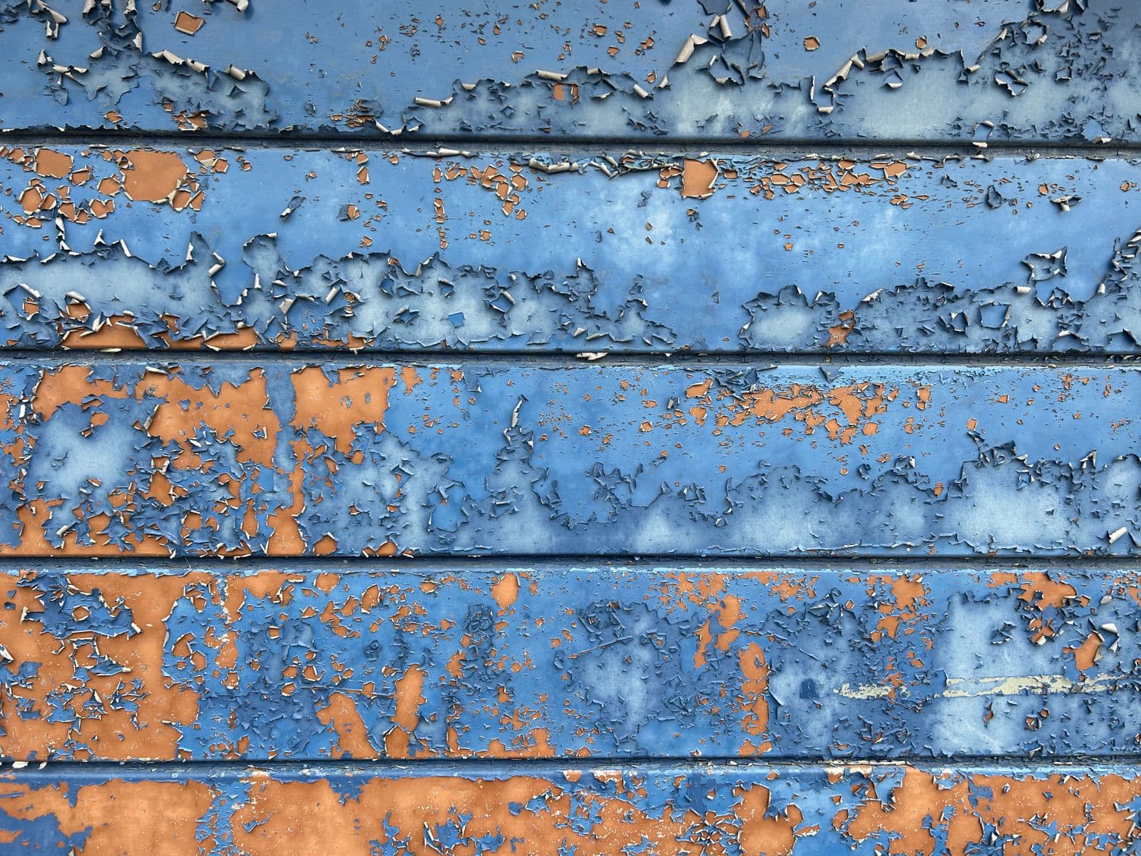 Blue paint flaking off an exterior wall